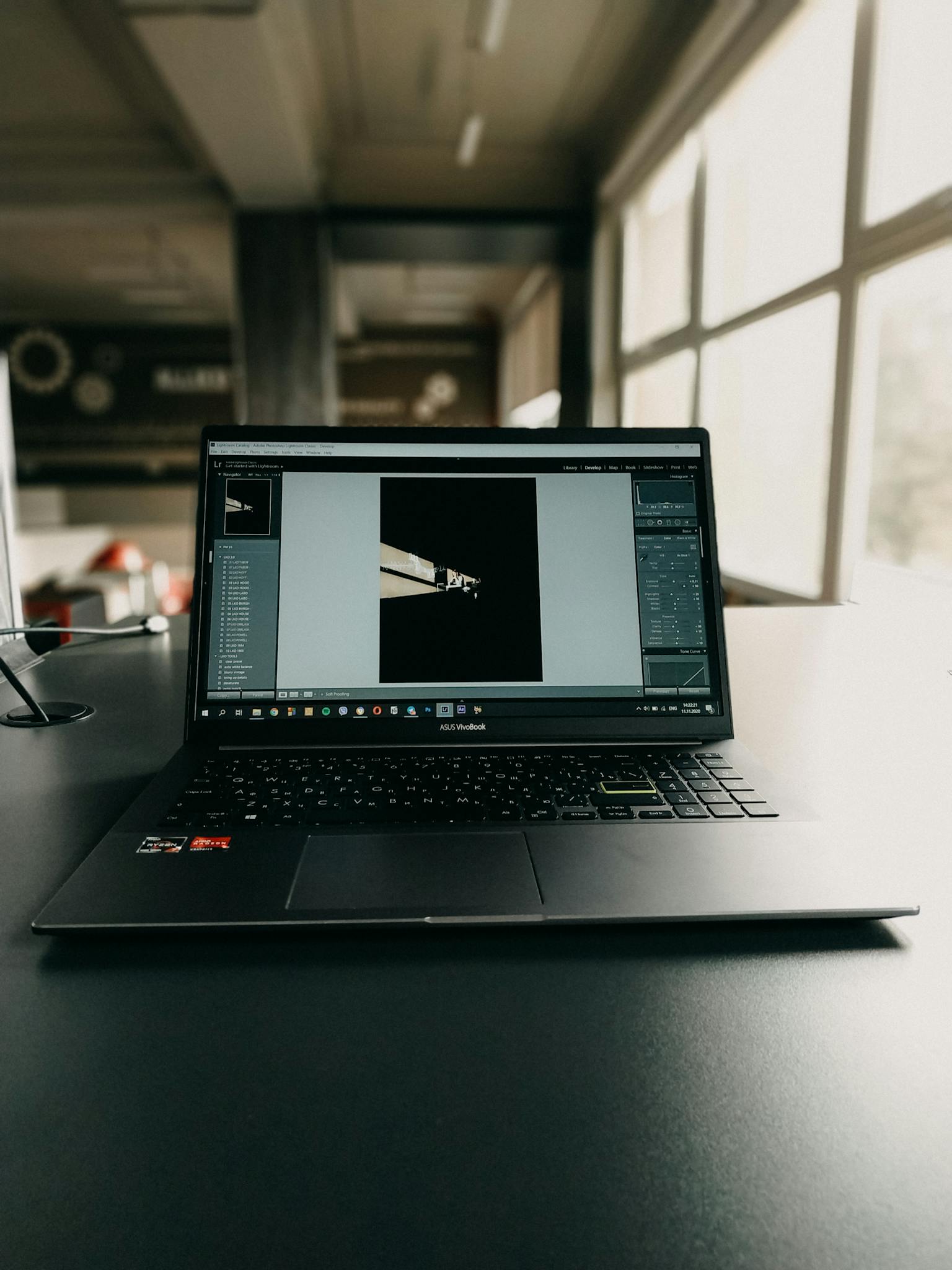 Laptop with photo editing software open on a desk in an office setting, showcasing a modern workspace.
